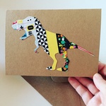 A handmade kraft paper card, featuring a T-Rex dinosaur collage crafted from colourful washi tape strips. The vibrant geometric patterns bring the roaring dinosaur to life with a unique, eye-catching